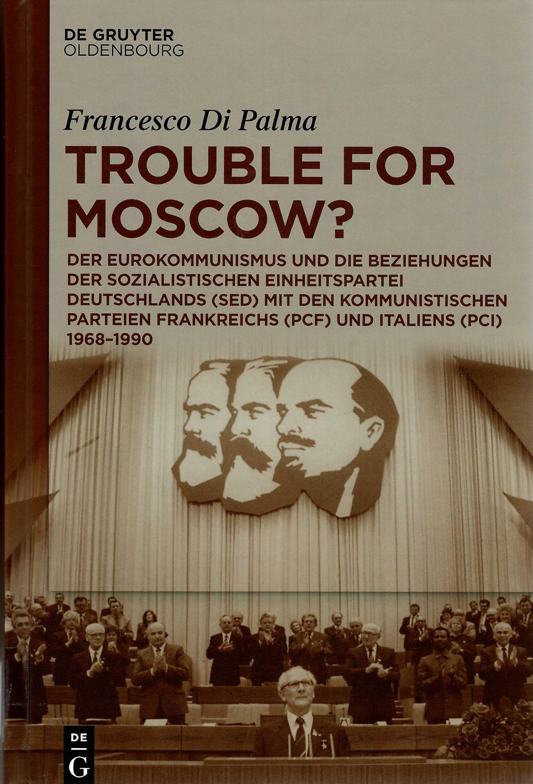 Das Buchcover zeigt ein sepia gefärbtes historisches Foto einer Rede von Erich Honecker . Hinter ihm applaudieren ihm Parteimittglieder. Über ihm im Saal an der Wand hängen die Profile von großen Kommunisten.